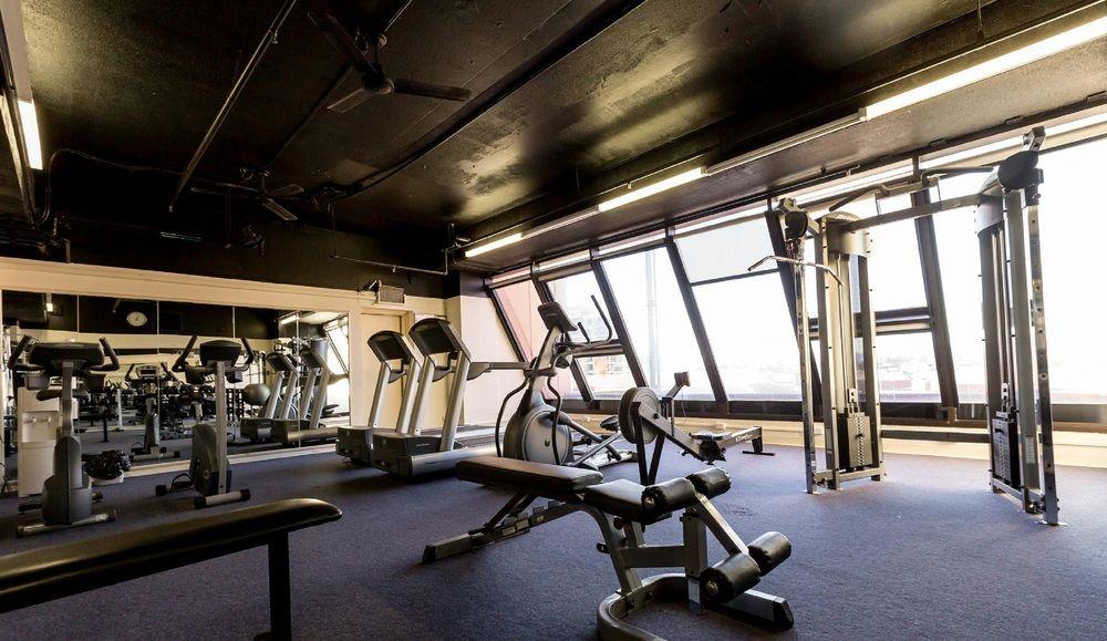 Stamford Grand Adelaide Hotel Glenelg Exterior photo The photo shows a modern gym interior with large windows that provide natural light. The space features various exercise equipment, including treadmills, a weight machine, and a multi-purpose bench. The flooring is carpeted, and the overall decor is 