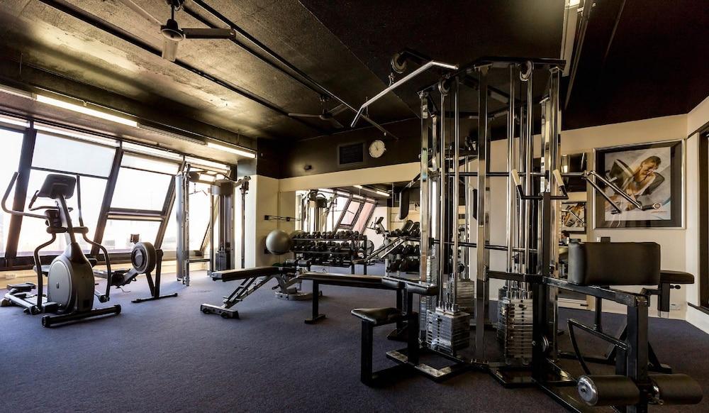 Stamford Grand Adelaide Hotel Glenelg Exterior photo The photo shows the interior of a gym or fitness room. It includes various exercise equipment, such as a multi-station weight machine and rowing machine. The space is well-lit with large windows allowing natural light in, and the walls are decorated 