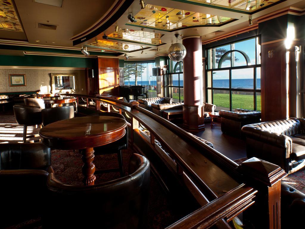 Stamford Grand Adelaide Hotel Glenelg Exterior photo The photo depicts a stylish and inviting interior of a lounge or bar. It features comfortable leather seating, wooden tables, and large windows that provide a view of the outdoors. The ceiling is adorned with decorative elements, and there’s a disco 