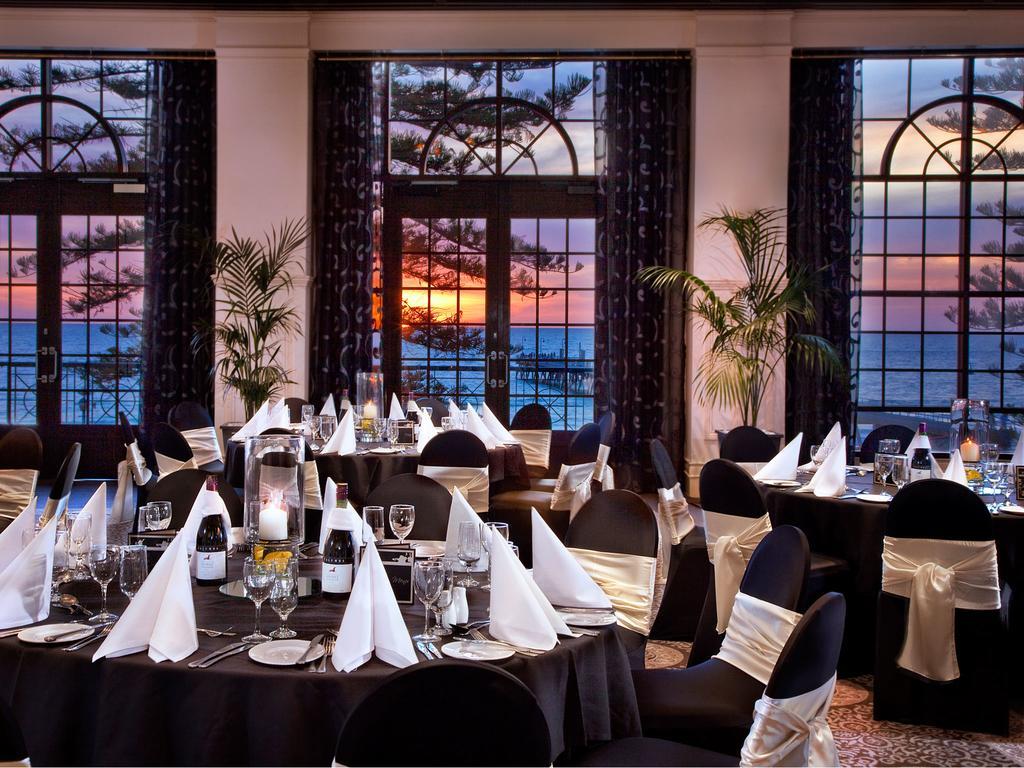Stamford Grand Adelaide Hotel Glenelg Exterior photo The photo shows an elegant dining setup inside a venue with large windows. The tables are adorned with black tablecloths and white napkins arranged in a stylish manner. Each table has glassware and other dining utensils placed neatly. In the backgrou